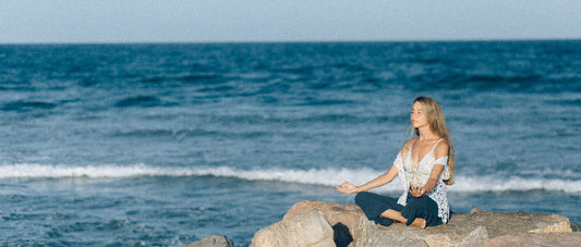 A woman meditating by the seaside, absorbing the tranquil benefits of aromatherapy, connecting with nature to relax and rejuvenate.