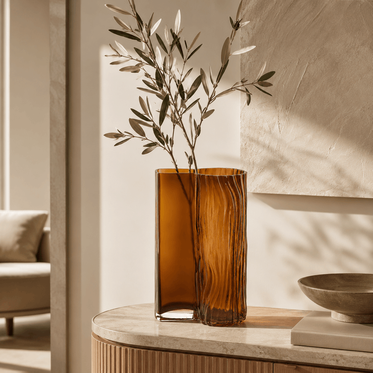 Amber decorative glass vase styled on a console table with olive branches