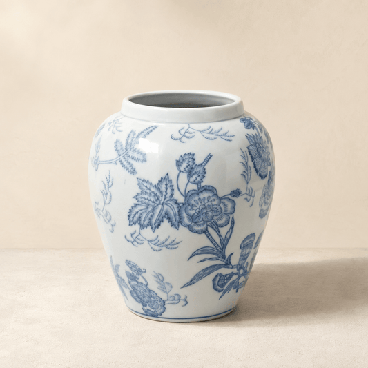 Blue and white botanical ceramic vase with a rounded urn shape on a warm ivory background