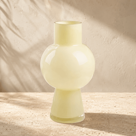 all ivory glass vase with a rounded sculptural center on warm ivory stone