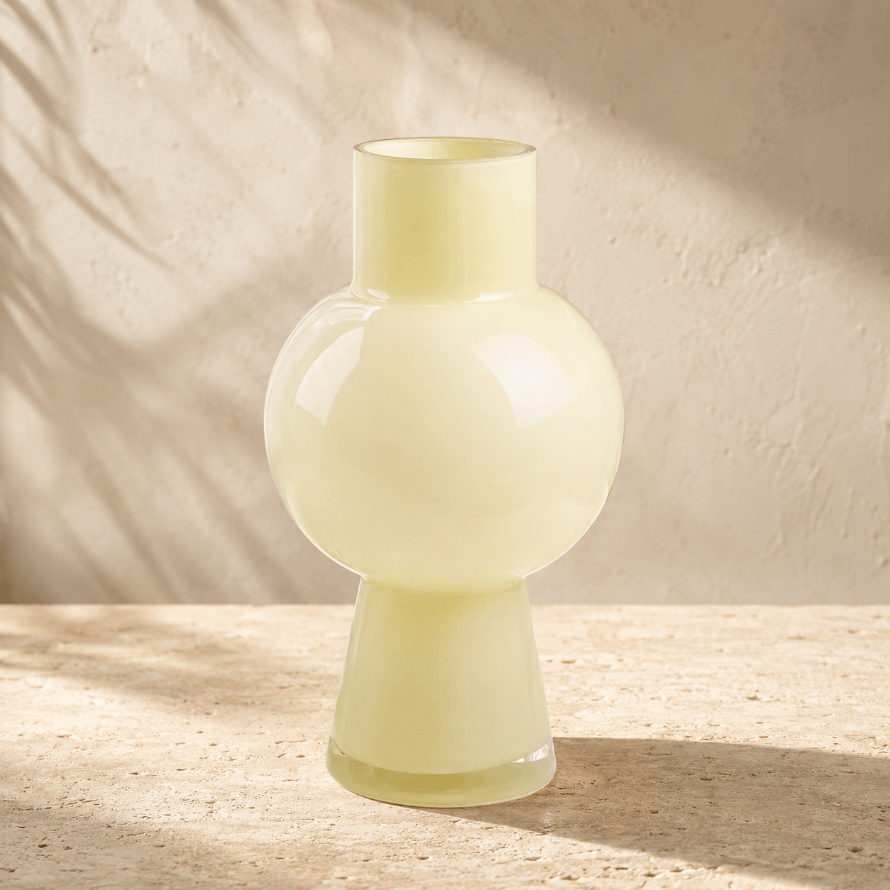 all ivory glass vase with a rounded sculptural center on warm ivory stone