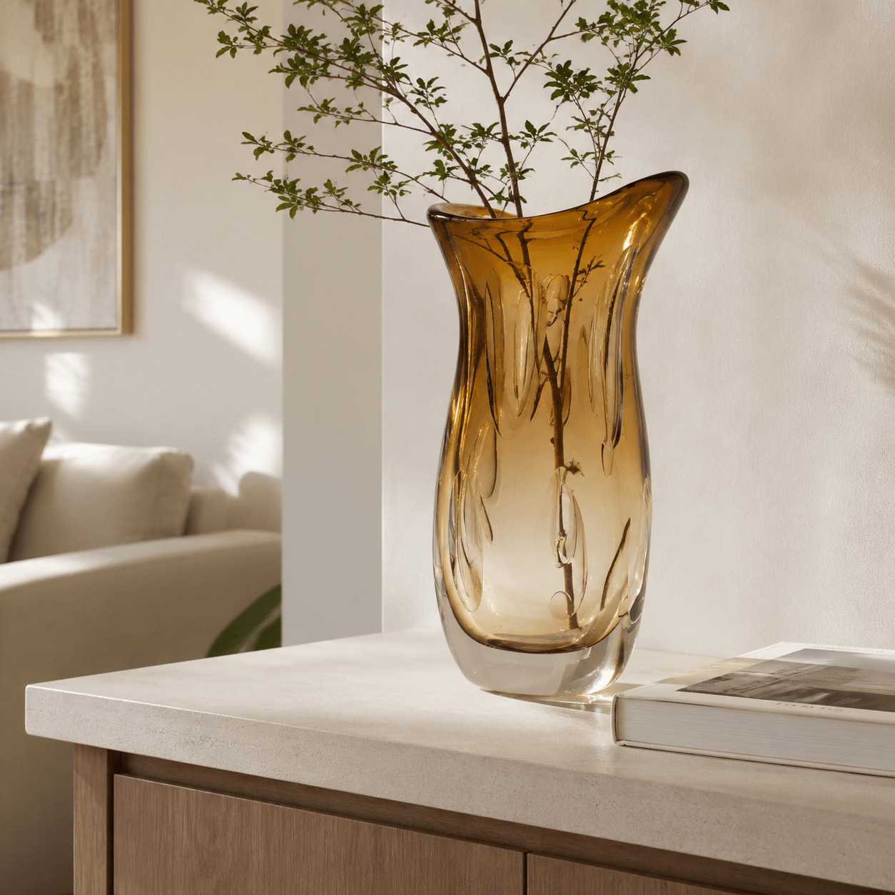 Amber sculptural art glass vase styled on a light stone console in a modern living room