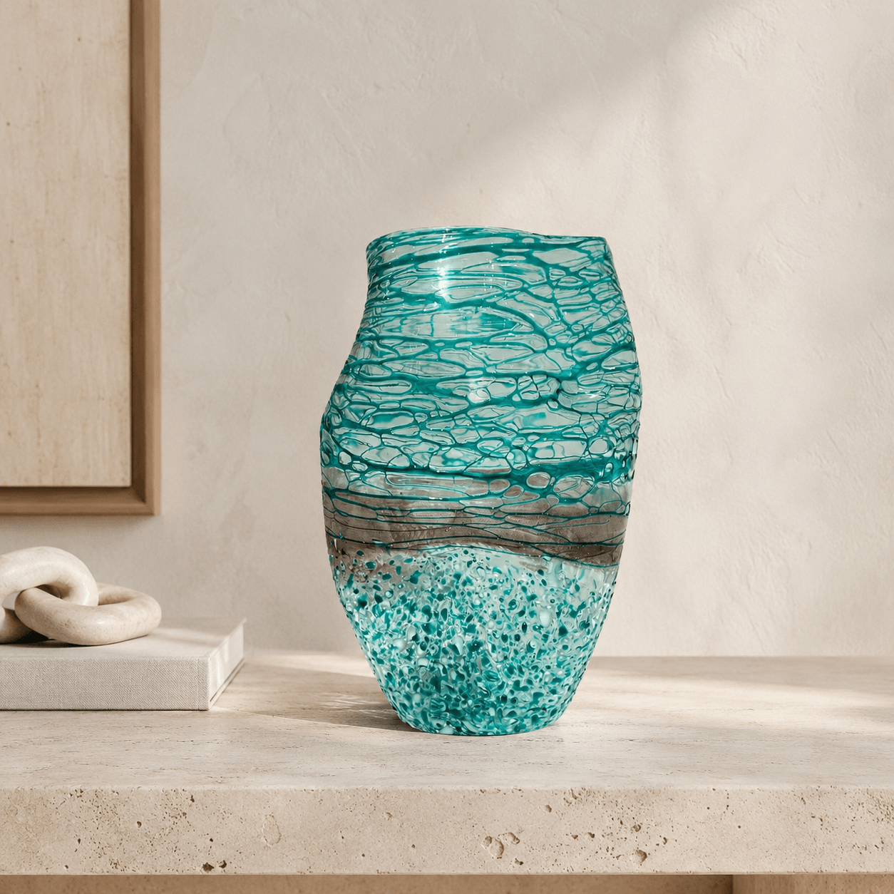 Blue green textured art glass vase styled on a light stone console