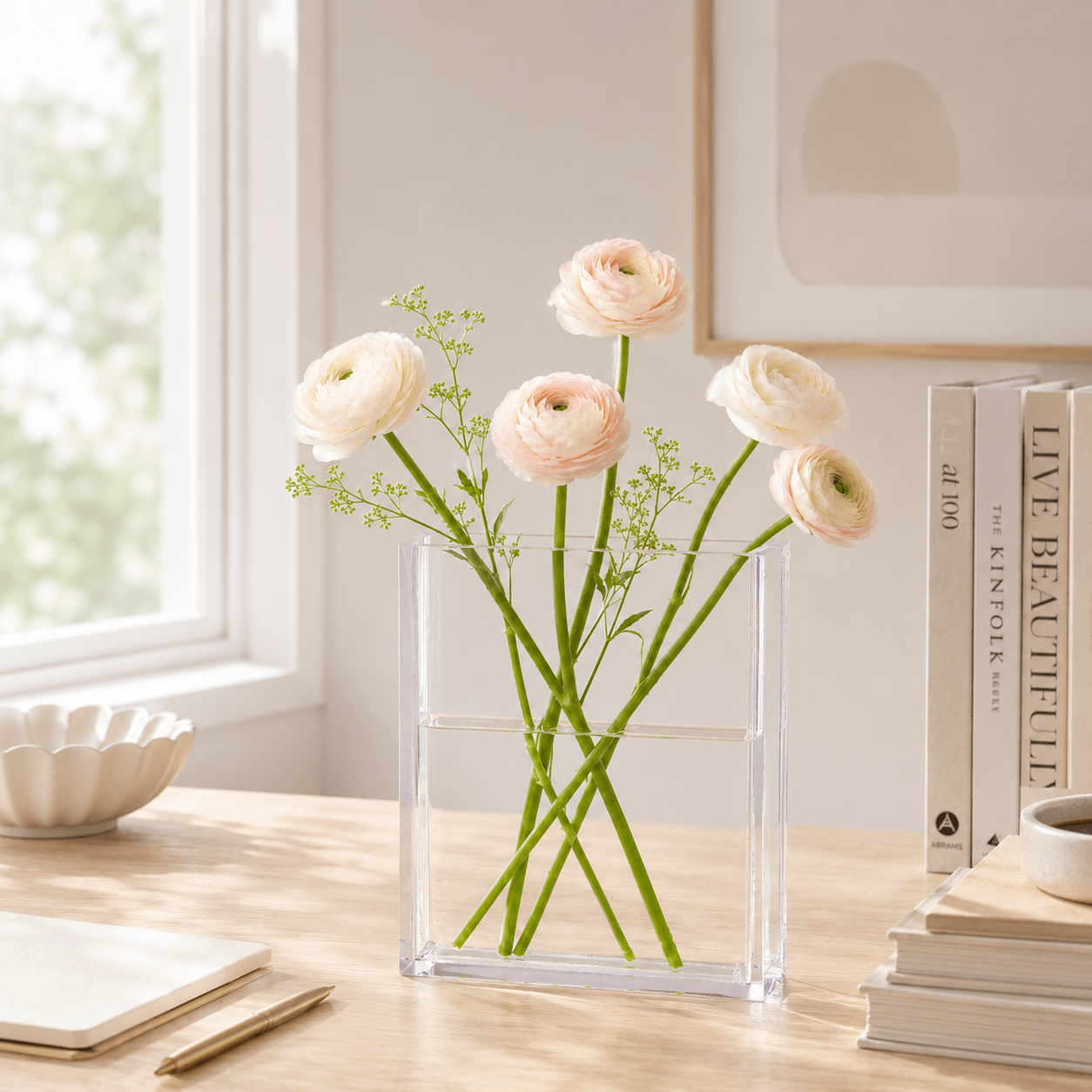 Book-shaped acrylic flower vase styled on a desk with fresh flowers and books.