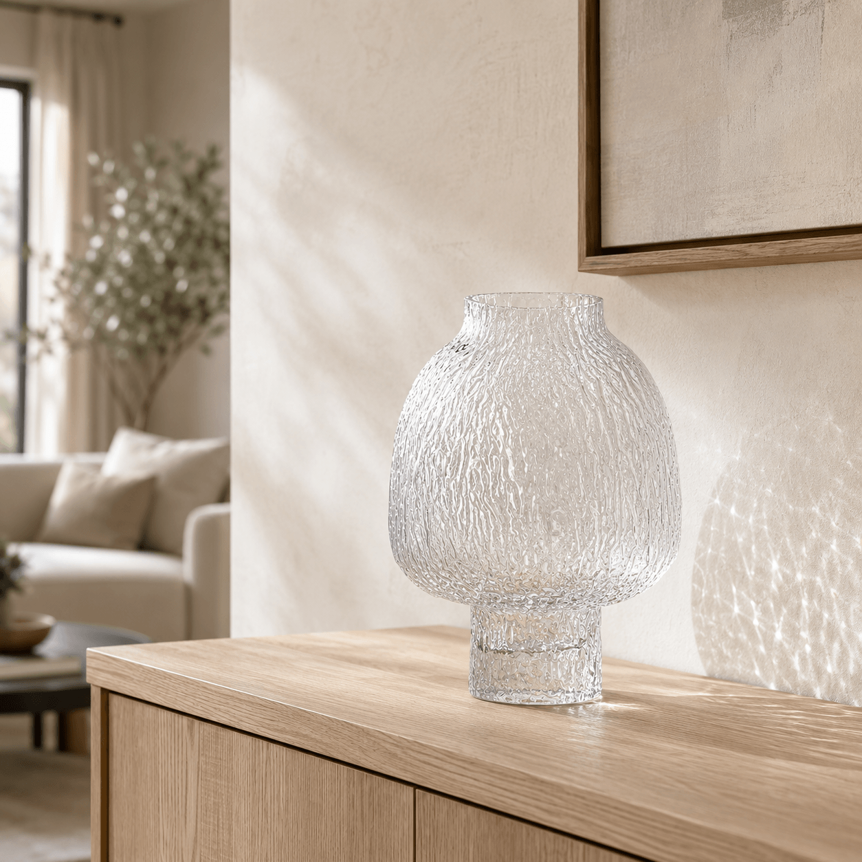 Clear textured glass vase displayed empty on a light oak console in a neutral living room