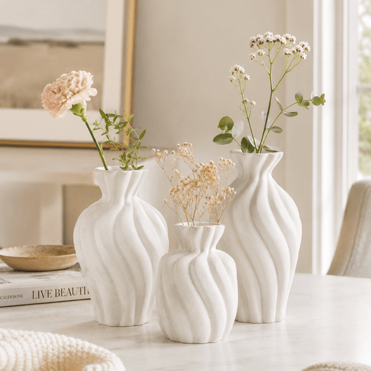 White wavy ceramic bud vase set styled with small flowers in a bright home setting.