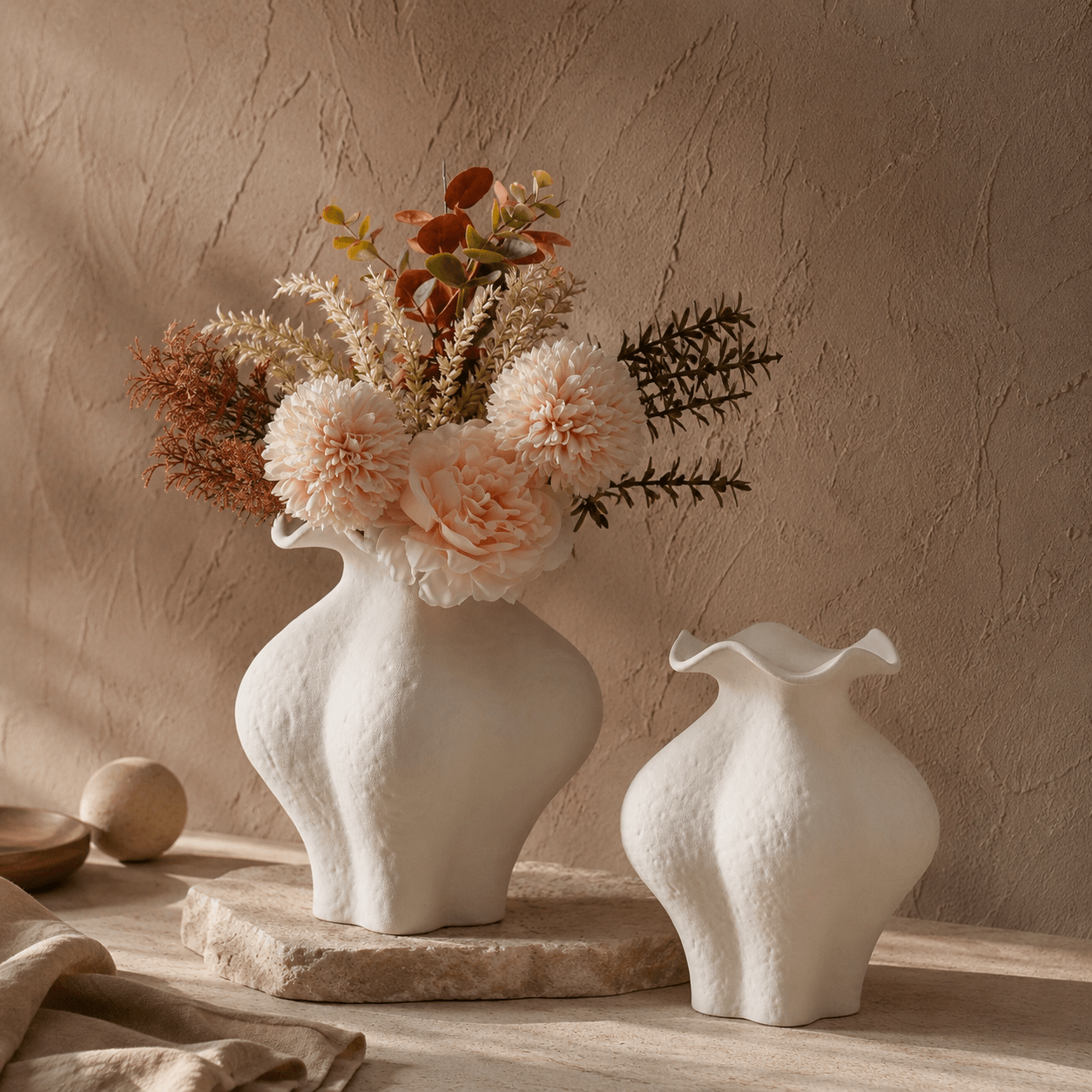 White petal ceramic vases styled with soft flowers in a warm home decor setting