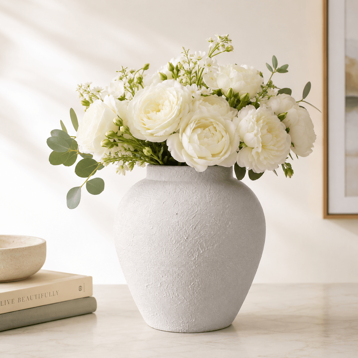 White textured ceramic vase styled with a full white flower bouquet.