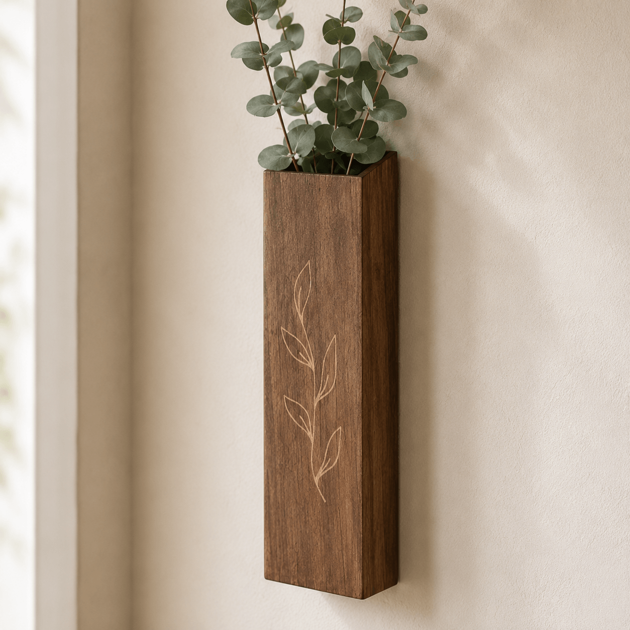 Single wooden wall pocket vase with eucalyptus stems in a close-up wall display.