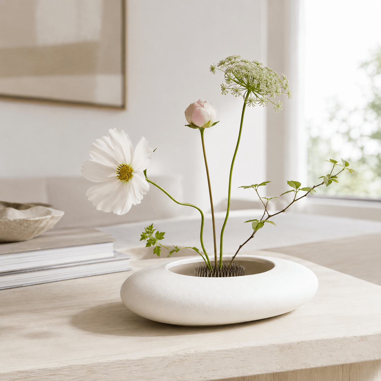 White ceramic ikebana bowl with a simple floral arrangement on a tabletop.