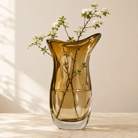 Amber art glass flower vase holding fresh branches with inner petal details visible