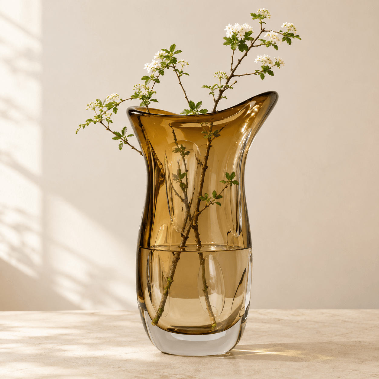 Amber art glass flower vase holding fresh branches with inner petal details visible