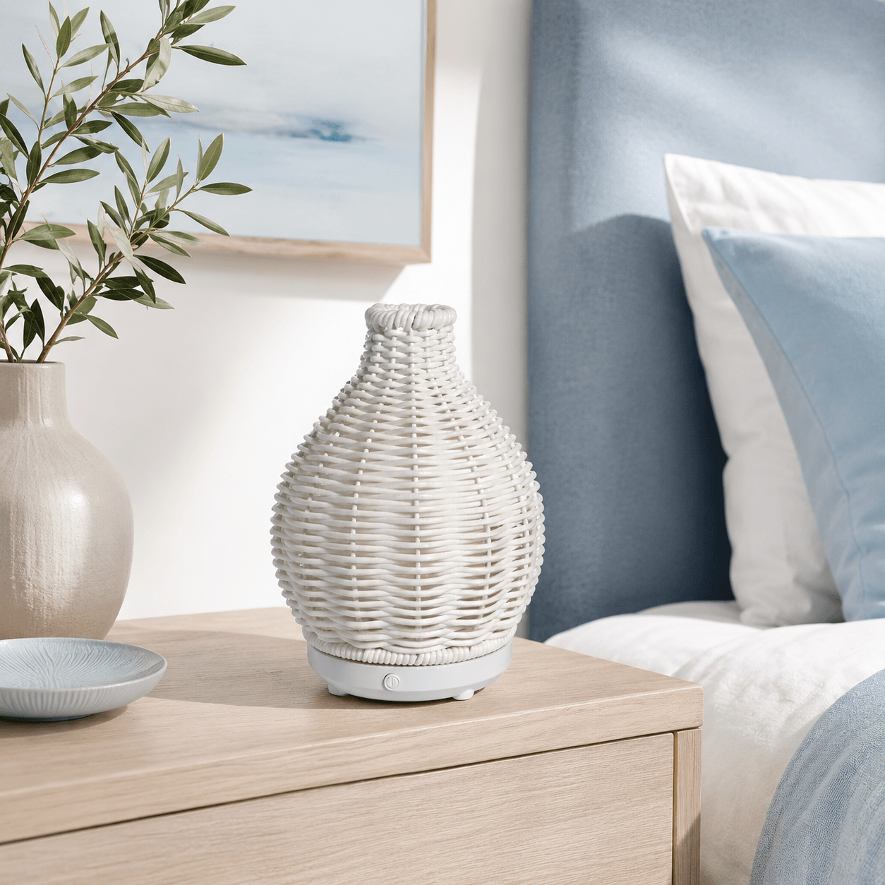White boho aroma diffuser on a light wood bedside table with soft neutral decor.