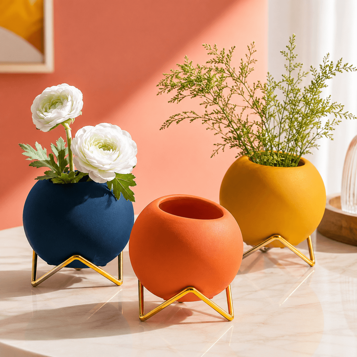 Set of blue orange and yellow round vases with gold stands on a modern tabletop