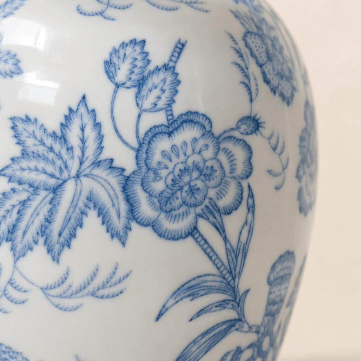 Muted blue botanical flowers and leaves beneath the glossy white ceramic glaze