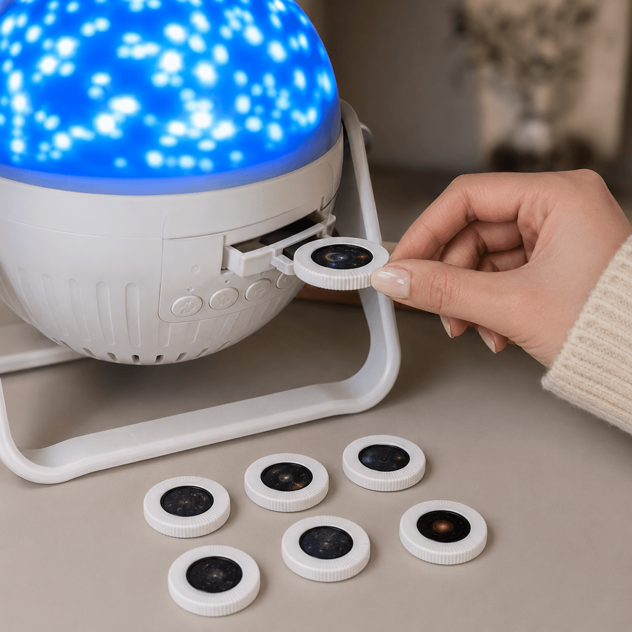 Hand changing a round projection film in the side drawer of the galaxy projector