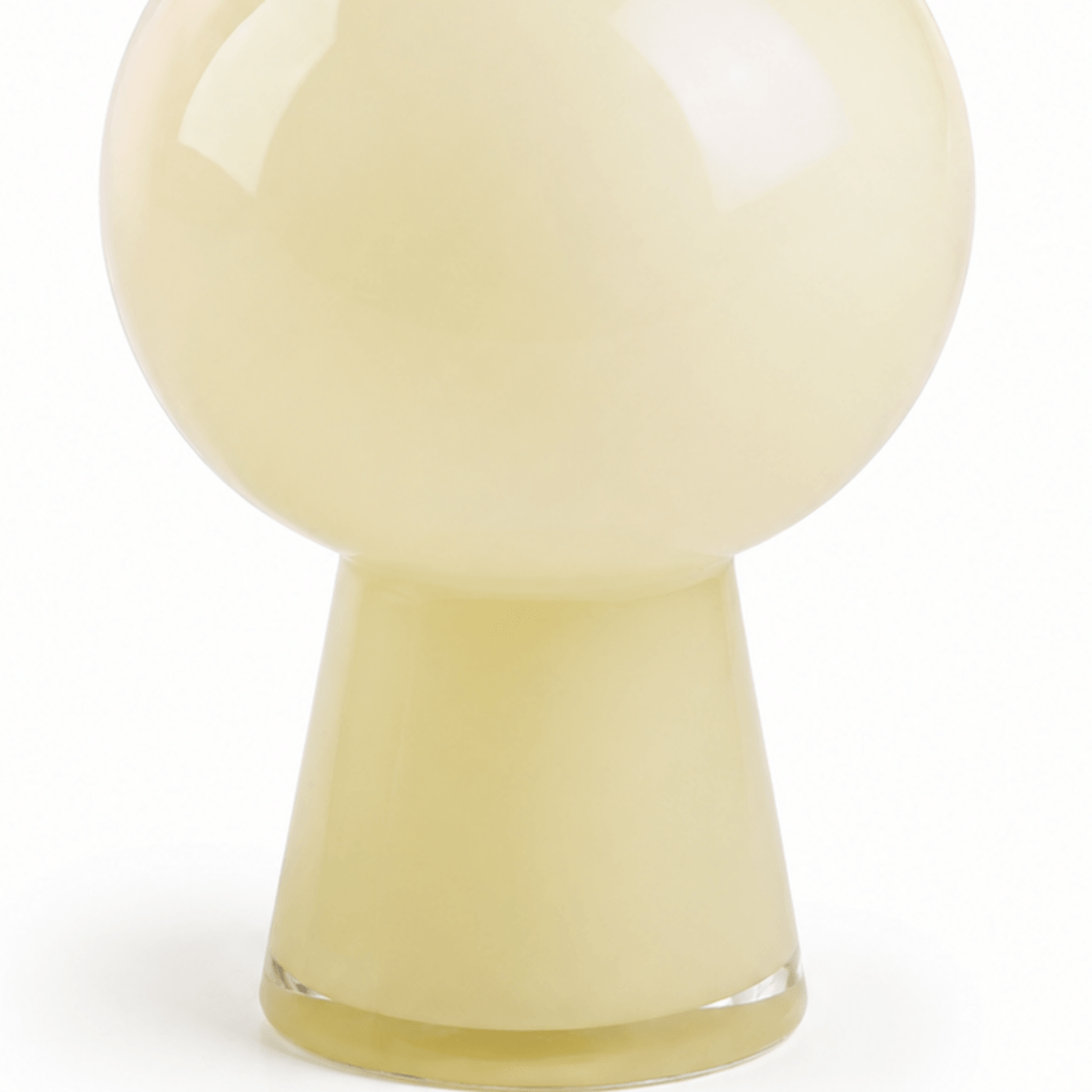 Close-up of the rounded center, tapered base, and clear foot of an ivory glass vase
