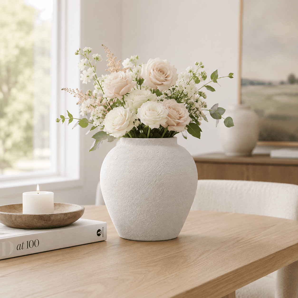 White textured ceramic vase styled with fresh flowers on a wooden table in a bright home setting.