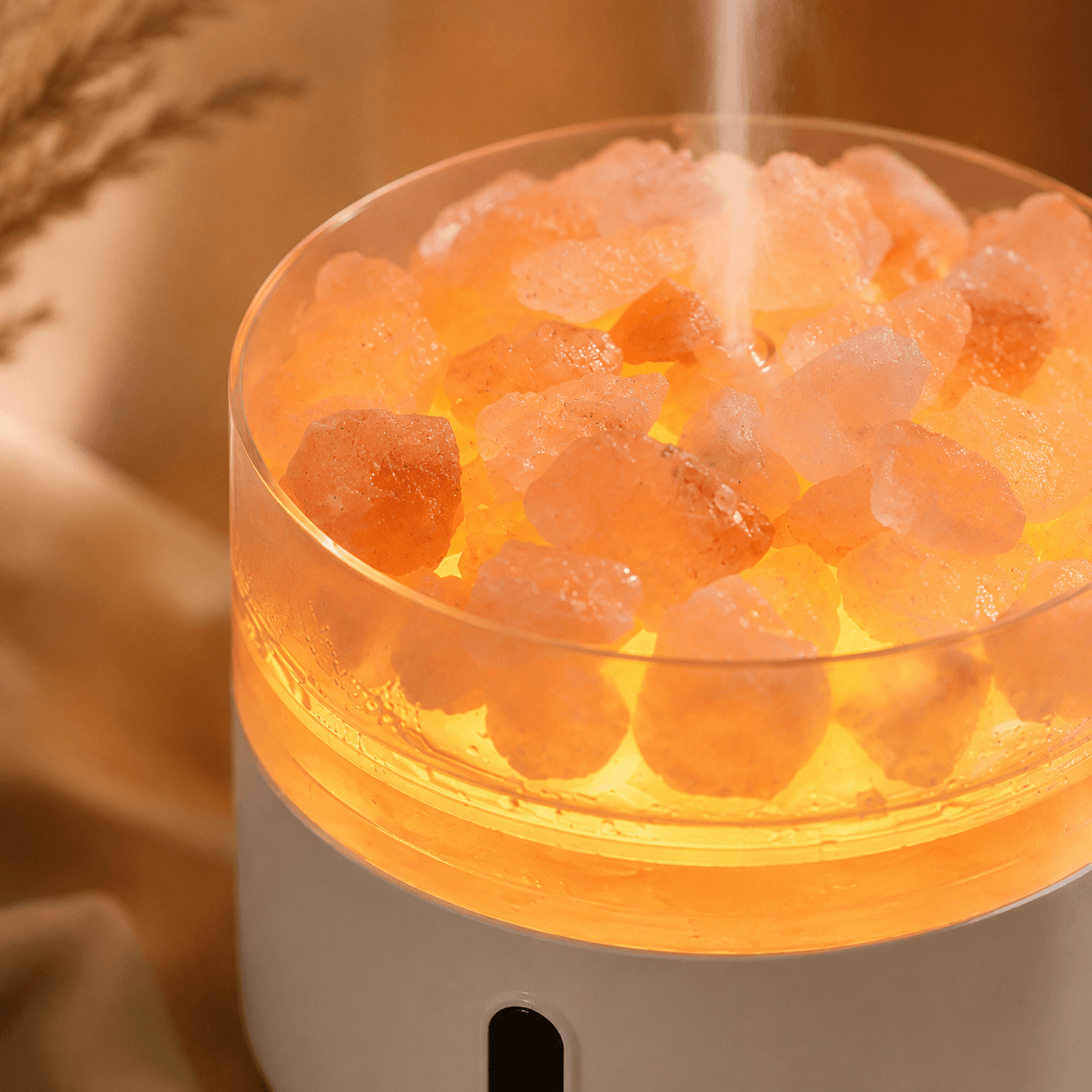 Close-up of glowing salt stones and soft mist on an aroma diffuser.