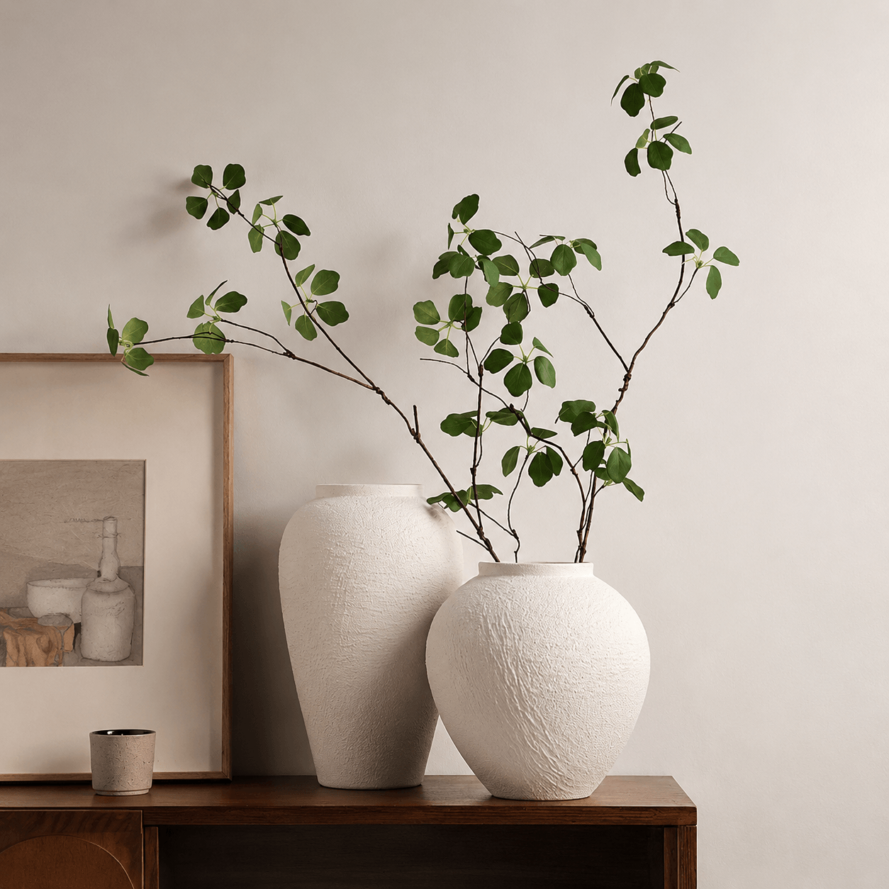 White textured vases styled with green branches on a wooden console