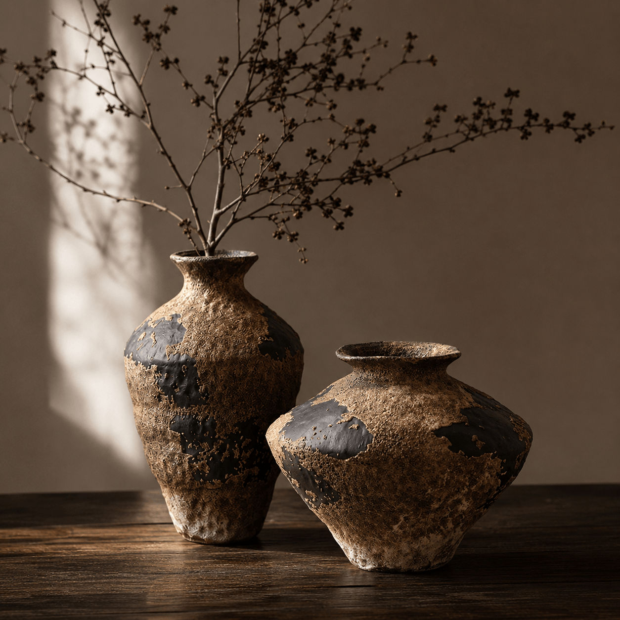 Wabi-sabi ceramic vase set styled on a dark wood table with warm shadow light
