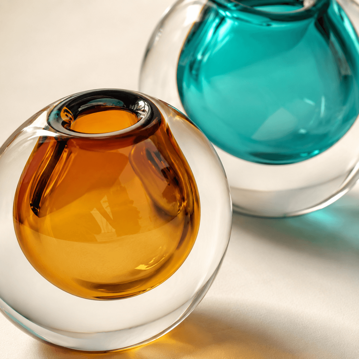Close-up detail of Amber and Peacock Blue color spectrum glass vases showing thick tinted glass.