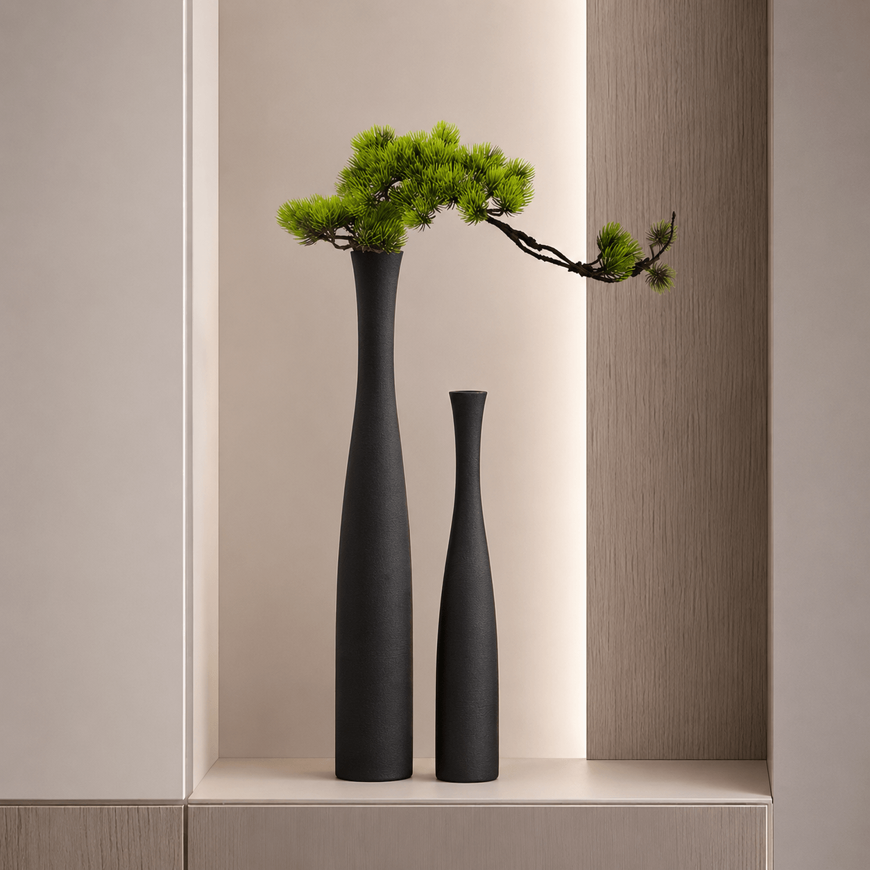 Matte black ceramic vase set styled with a faux pine branch on a round side table.